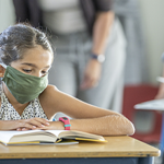 Young student in classroom wearing mask