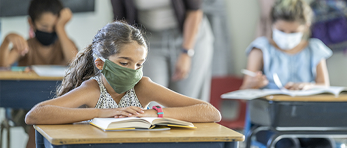 Young student in classroom wearing mask