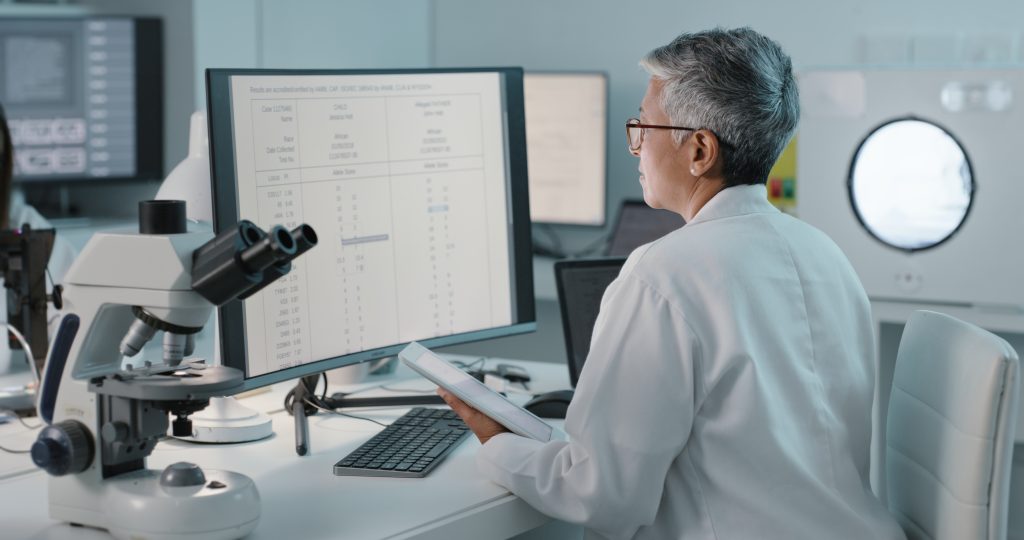 women scientist looking at her tablet and computer. researching somthing