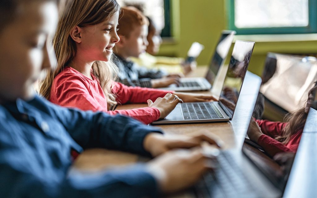 young students learning on laptops in classroom