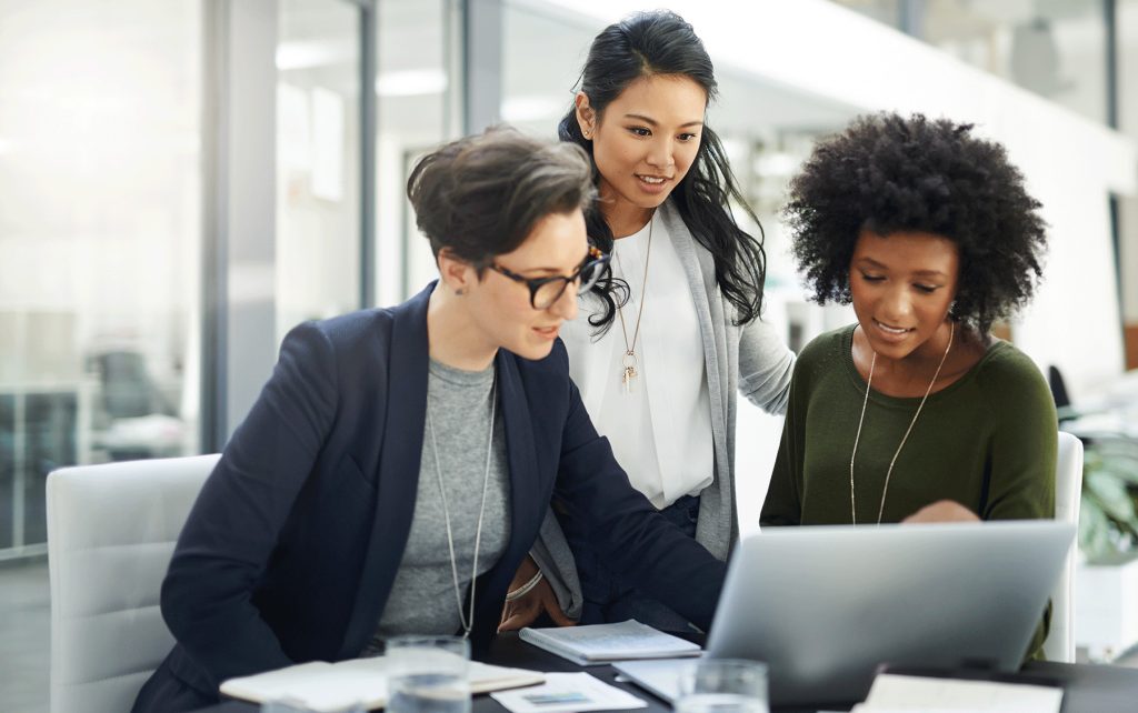 three business colleagues collaborate over a laptop in an office