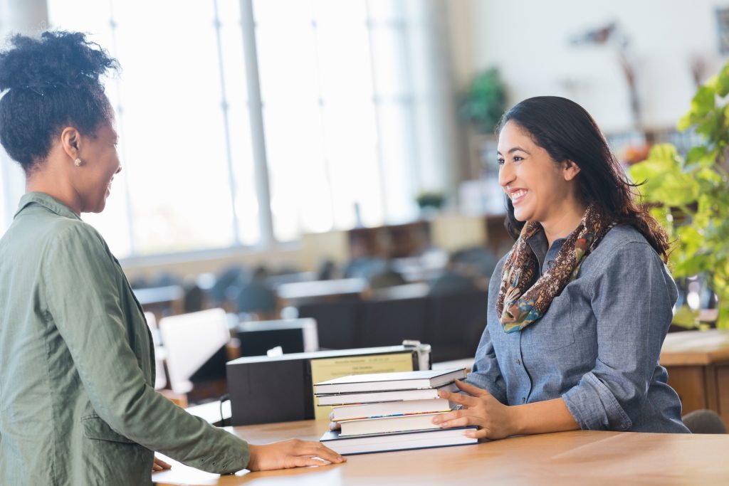 Adult student checking out books in local college library