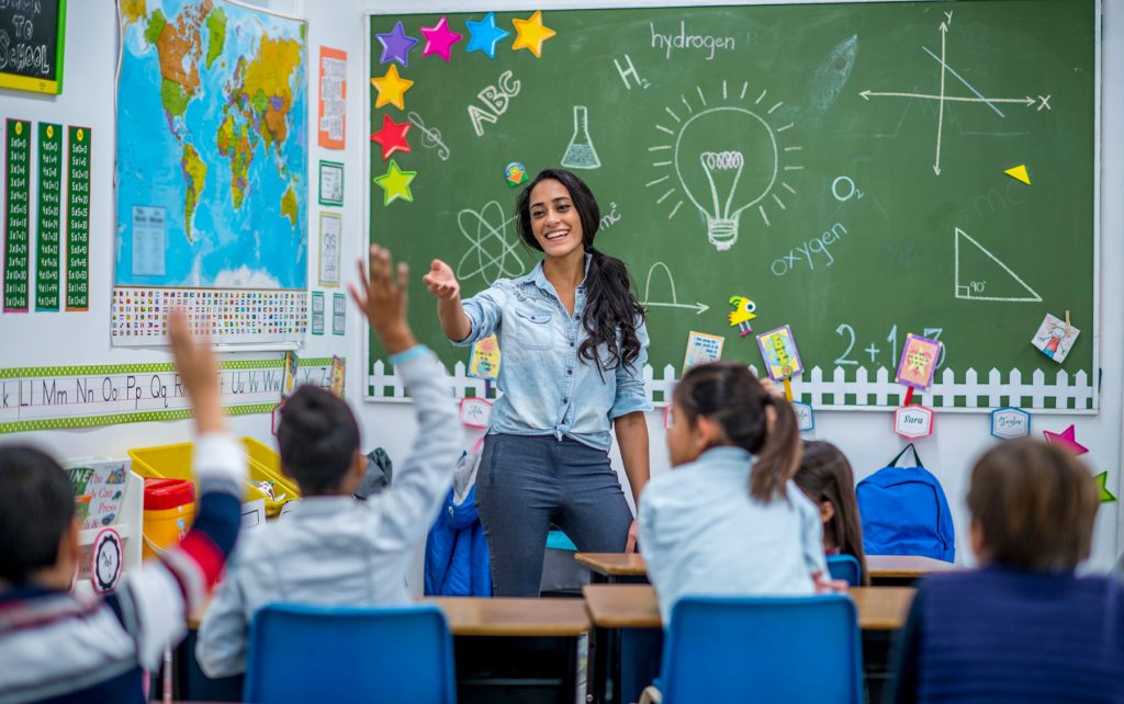 teacher in front of chalkboard with students