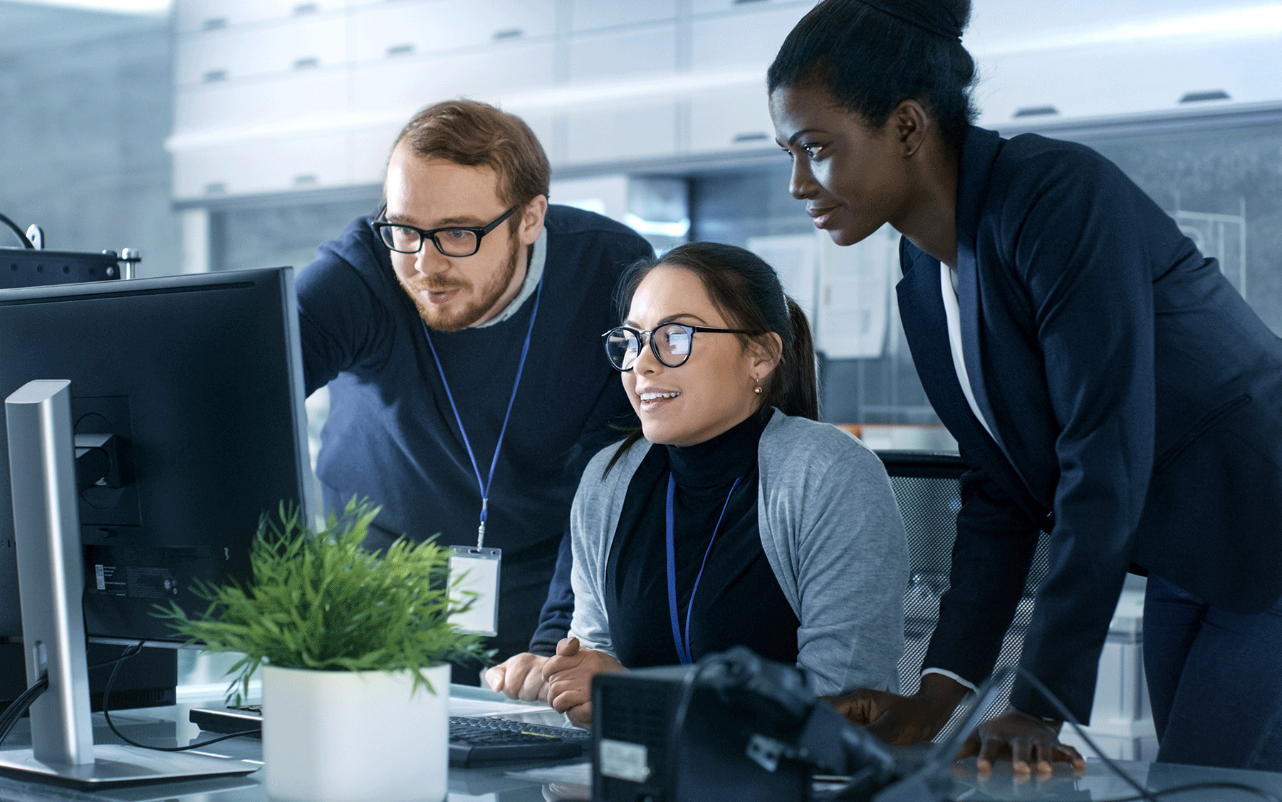 three colleagues collaborate on an office computer