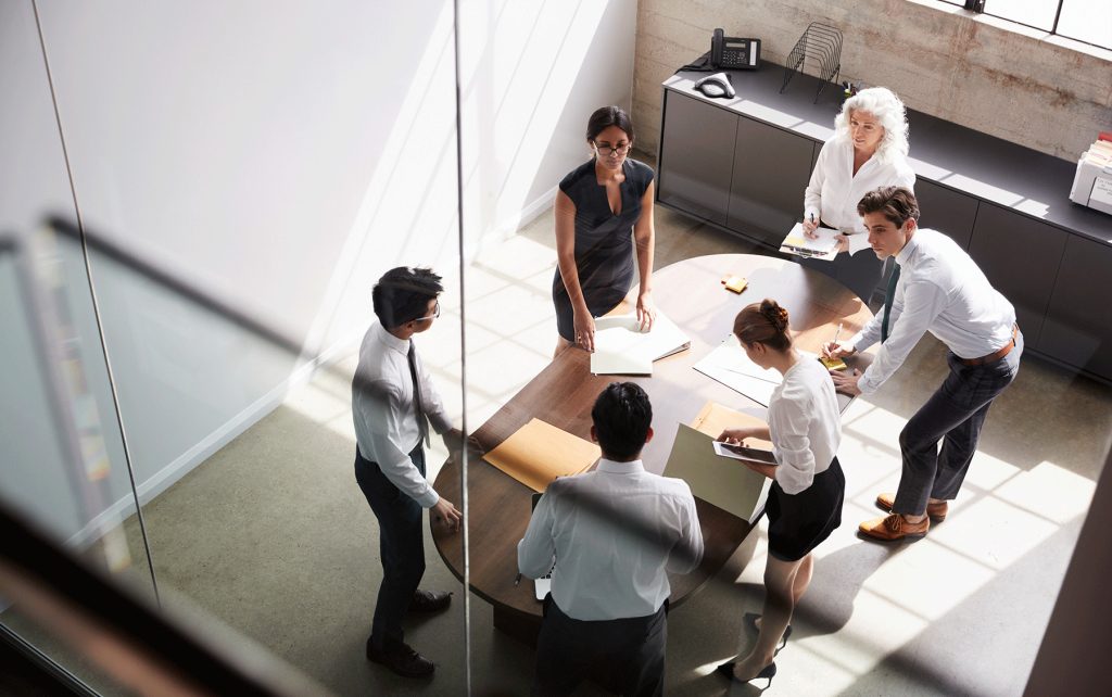 colleagues gathered around a table in a glass-walled conference room