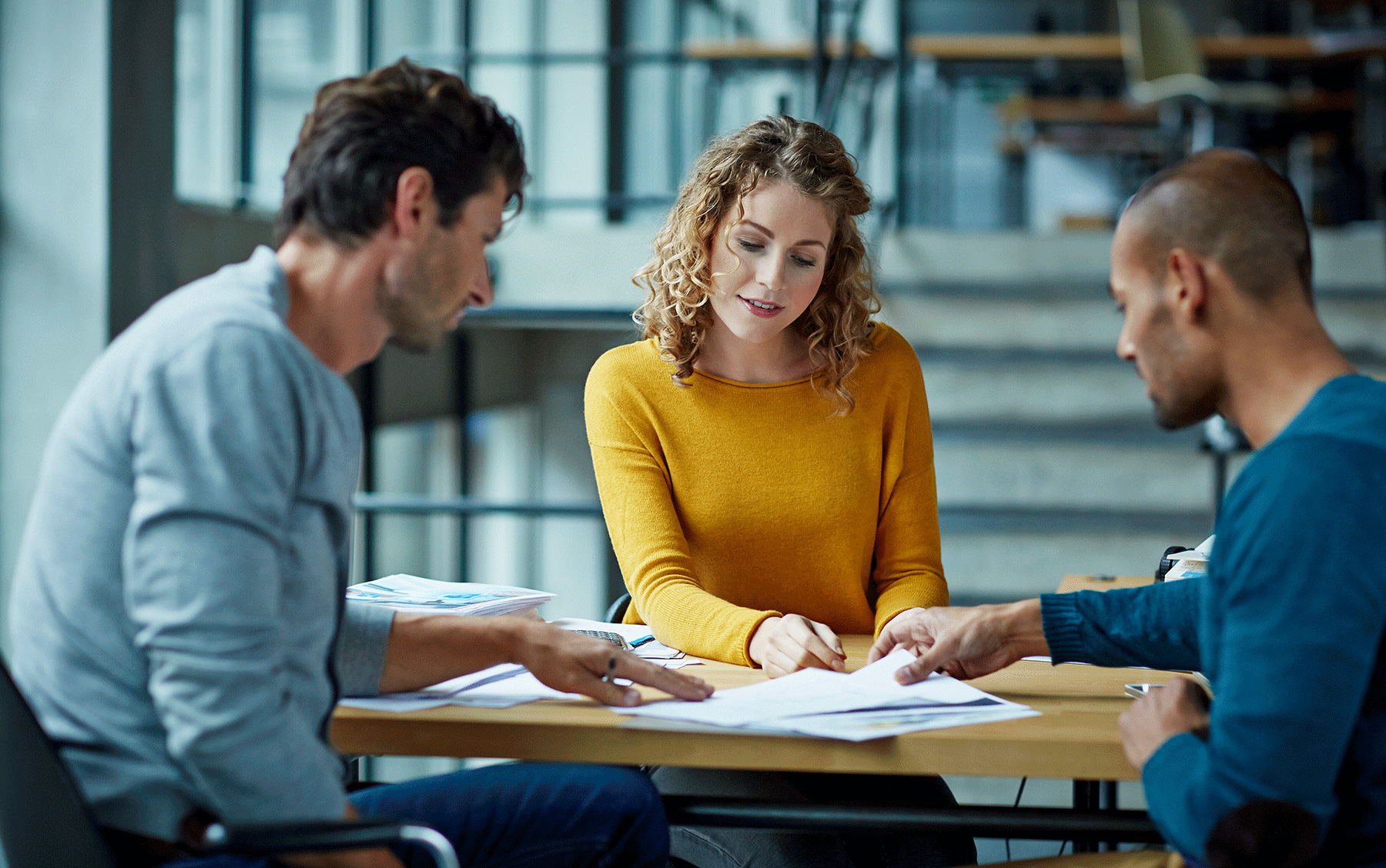 three colleagues comparing notes at conference table
