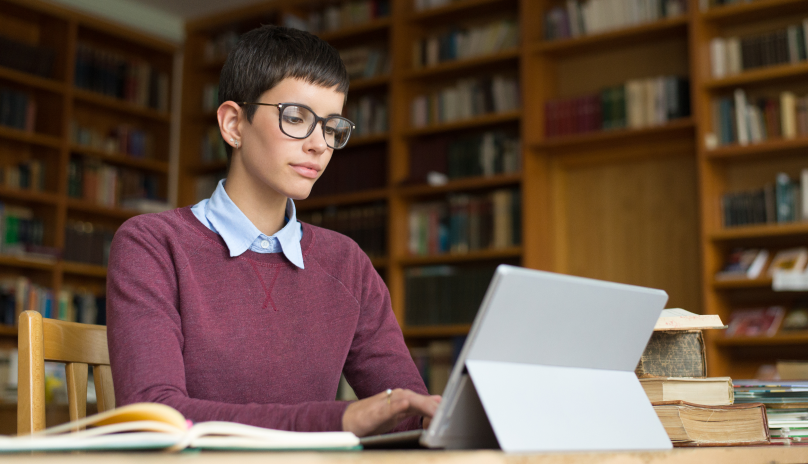 female professional typing on tablet in library