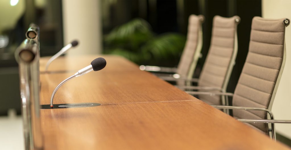 table with empty chairs and microphones