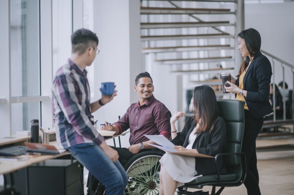 man in a wheelchair socializing with co workers