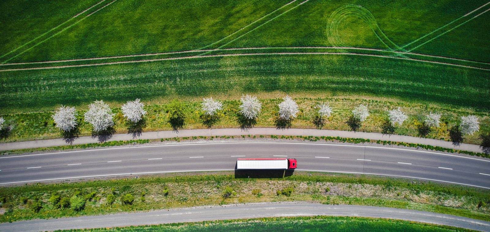 Drone shot direct above a truck moves along a single road.