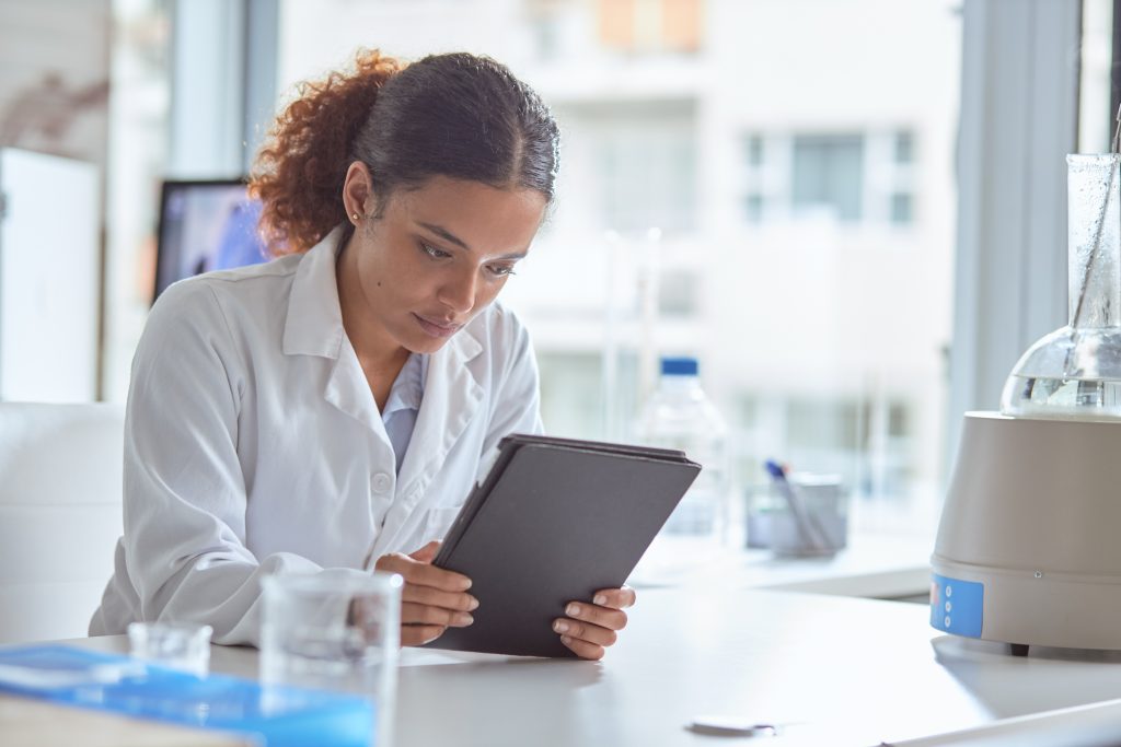 Scientist dressed in lab coat using a digital tablet in lab