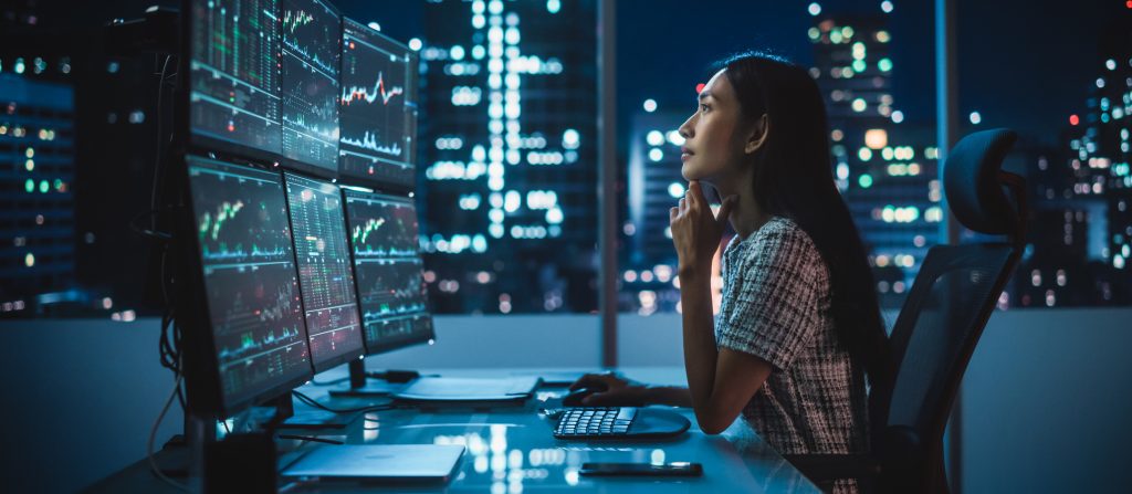 Portrait of a Financial Analyst Working on Computer with Multi-Monitor Workstation with Real-Time Stocks