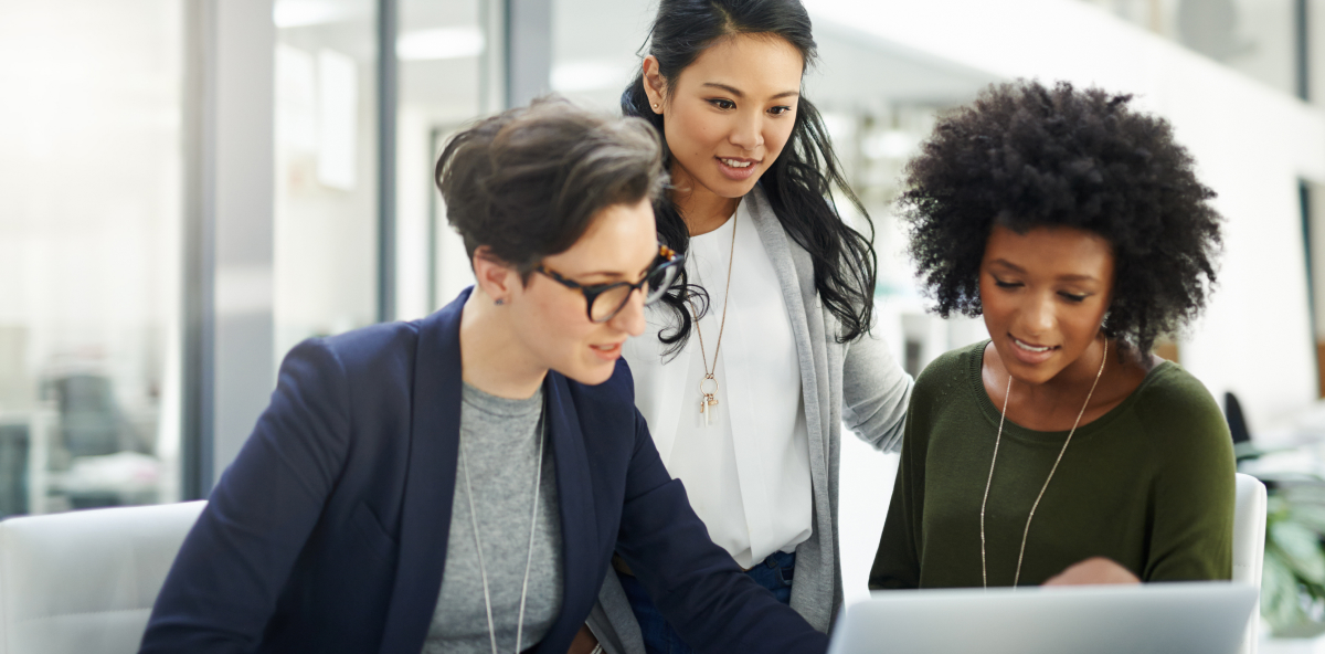 three business colleagues collaborate over a laptop in an office