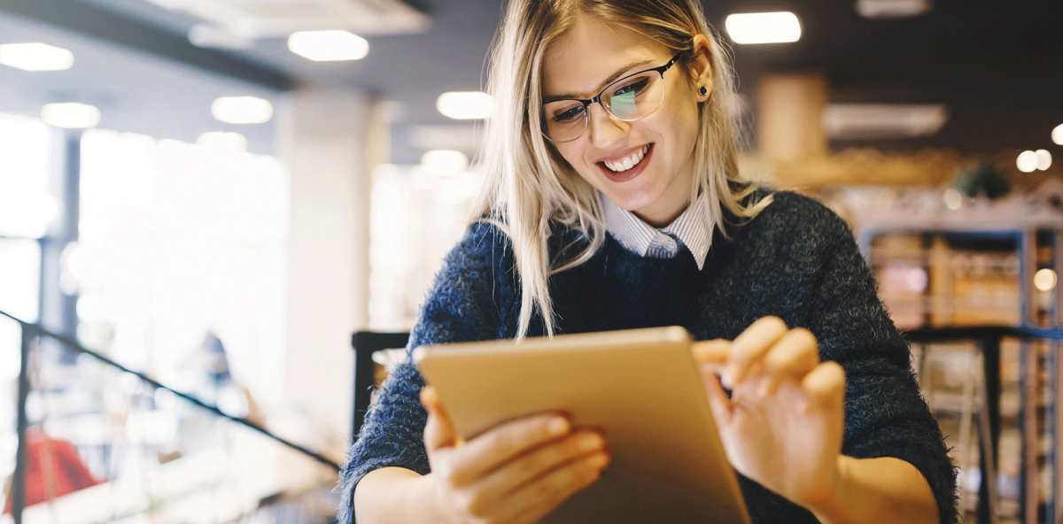 female student studying on tablet in library setting