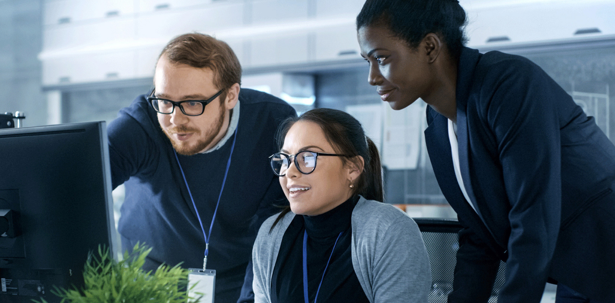 three colleagues collaborate on an office computer