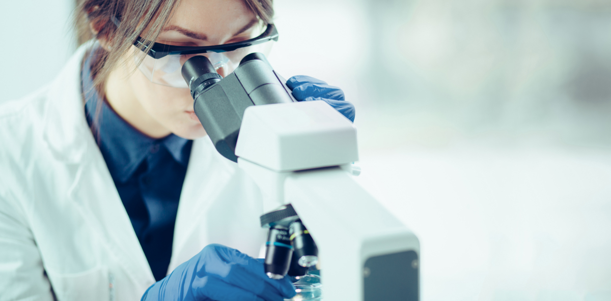 female scientist looking through microscope in lab