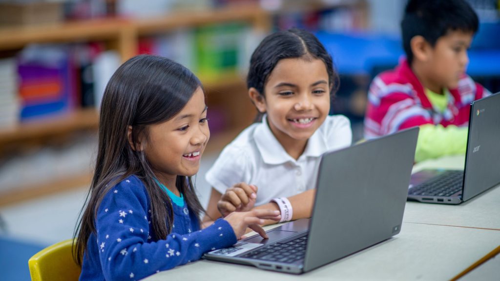 young students smiling while learning on their laptops
