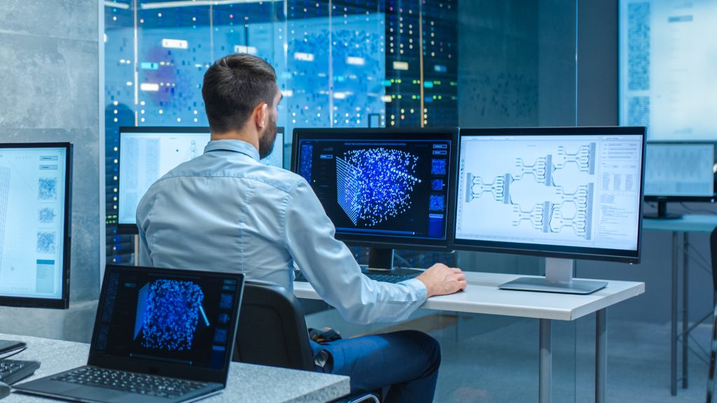 Male computer engineer looking into his displays which shows 3D representations of neural networks